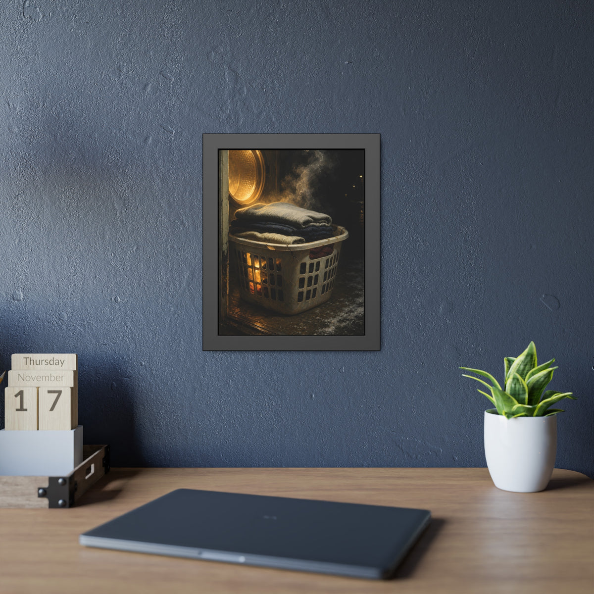 A laundry basket of folded clothes glowing in front of an open dryer. The Warm Clothes Against the Cold by Garabaggio, framed fine art print hanging in a room.