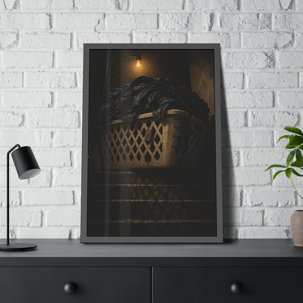 A laundry basket heaped with clothes on stairs under a bare bulb. The Overload on the Basement Stairs by Garabaggio, framed fine art print hanging in a room.