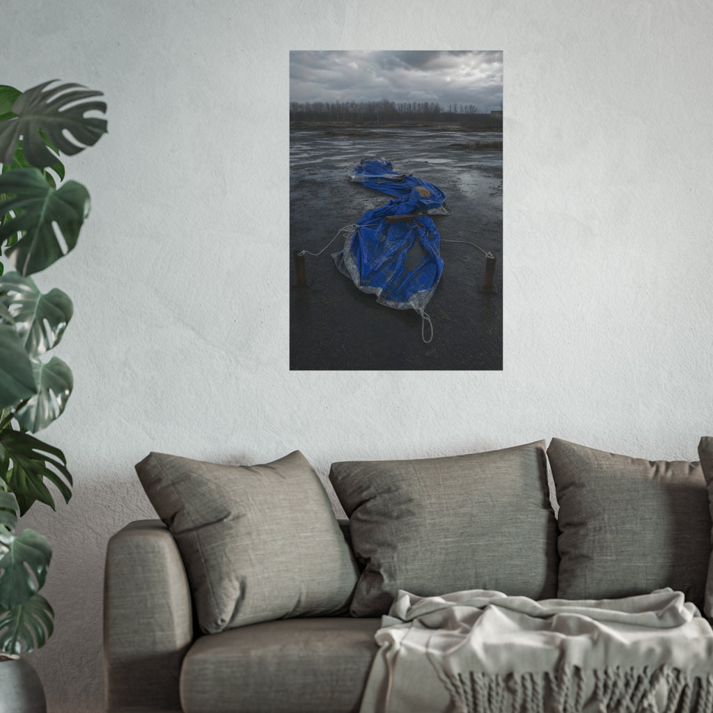 Collapsed blue tarp roped between two posts on wet cracked ground. Collapse Under Wind by Garabaggio, fine art print hanging in a room.