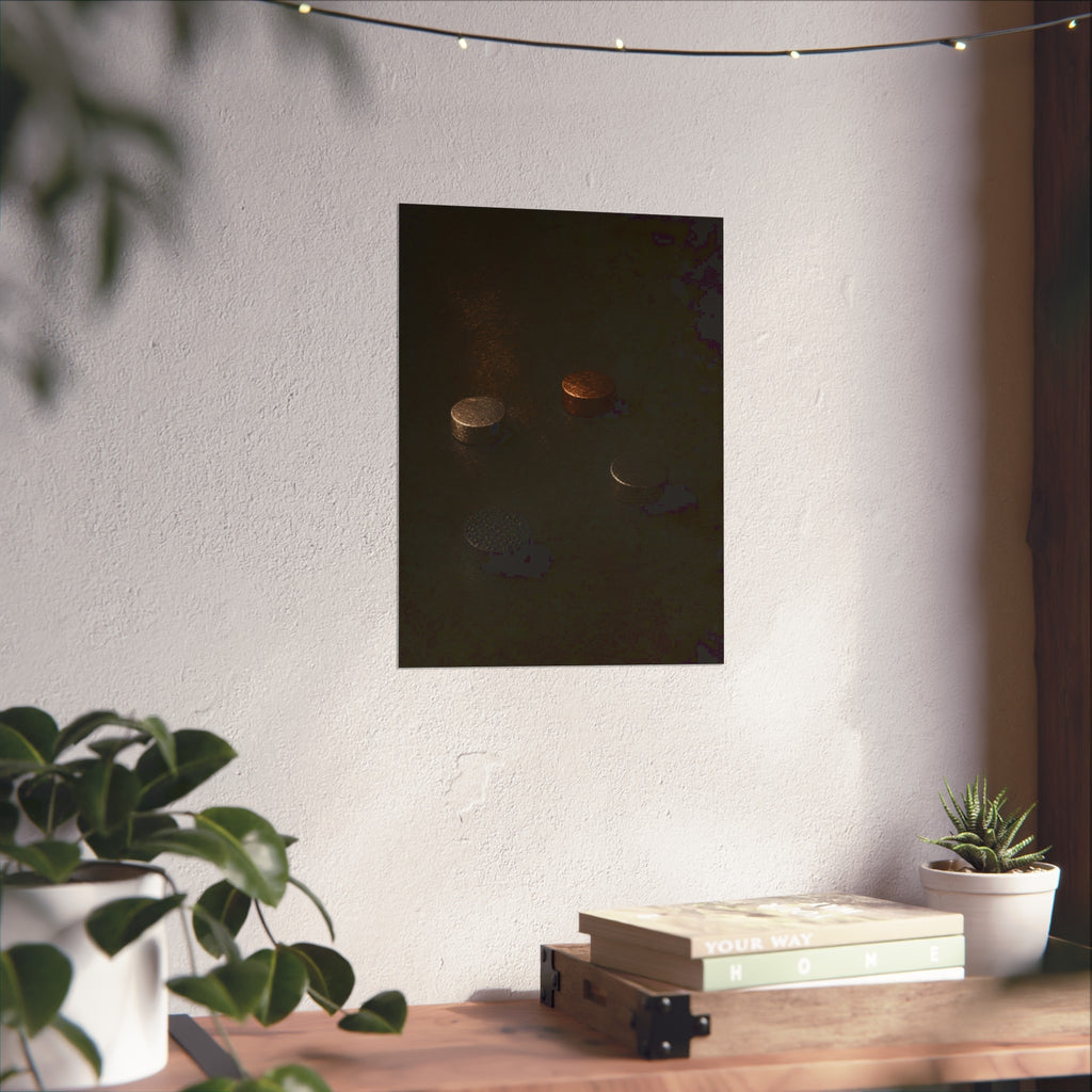 Four small metal discs on a dark scuffed surface in a narrow beam of light. Metals After the Song by Garabaggio, fine art print hanging in a room.