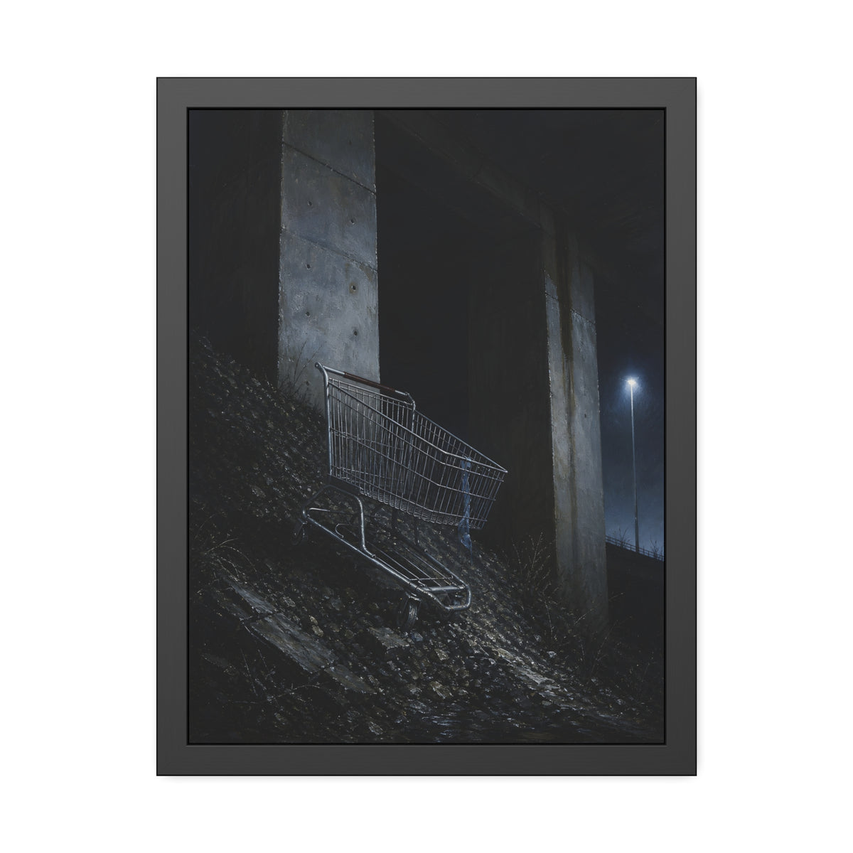 A shopping cart on a rocky slope under an overpass near a streetlamp. The Descent to the Underpass by Garabaggio, framed fine art print, 18″ x 24″.