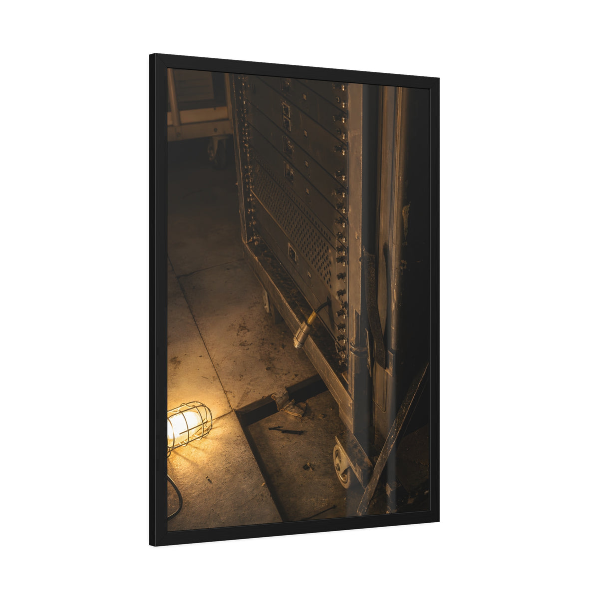 A server rack on a concrete floor beside a caged work light. The Silence at Cutover by Garabaggio, framed fine art print hanging in a room.