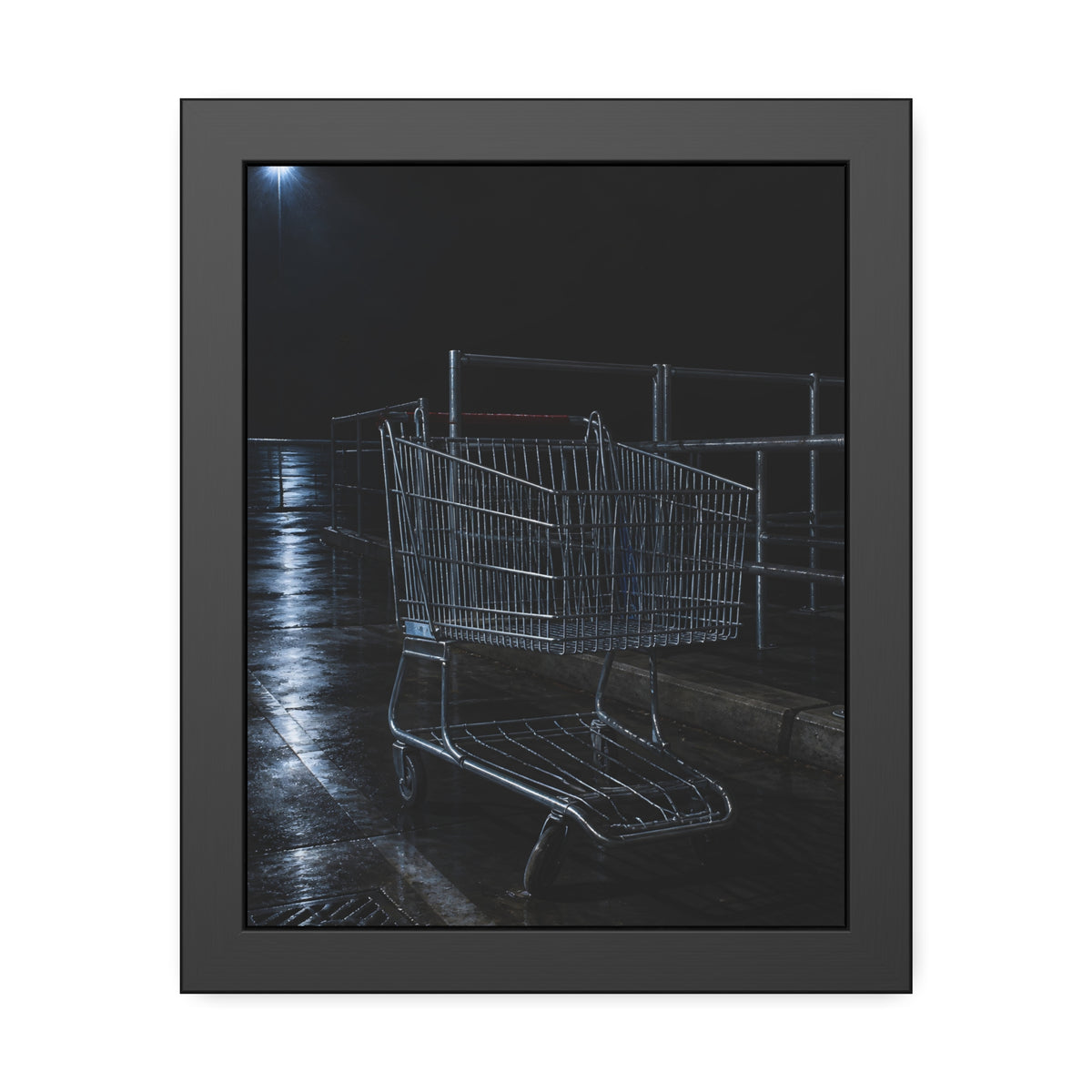 A shopping cart beside its corral on wet asphalt under a lot light. The Cart at the Corral by Garabaggio, framed fine art print, 11″ x 14″.