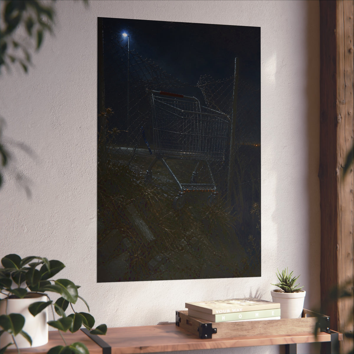 A shopping cart wedged in a chain link fence under a streetlamp. The Abandonment at the Ravine Fence by Garabaggio, fine art print hanging in a room.