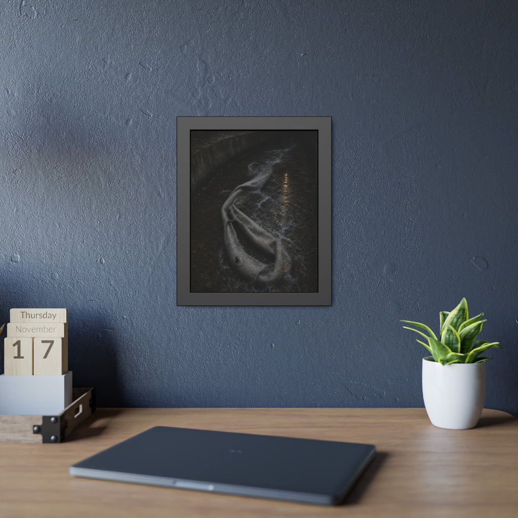 A deflated pool float caught in a concrete drainage channel of running water. The Release into Runoff by Garabaggio, framed fine art print hanging in a room.