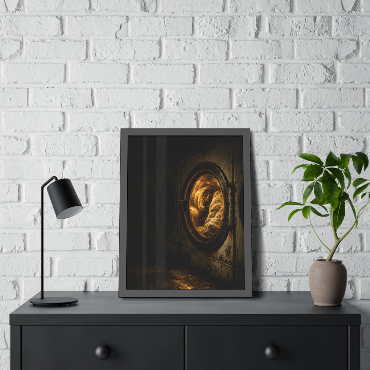 A row of dryers with one drum lit and tumbling in a dark laundromat. The Last Dryer Turning by Garabaggio, framed fine art print hanging in a room.