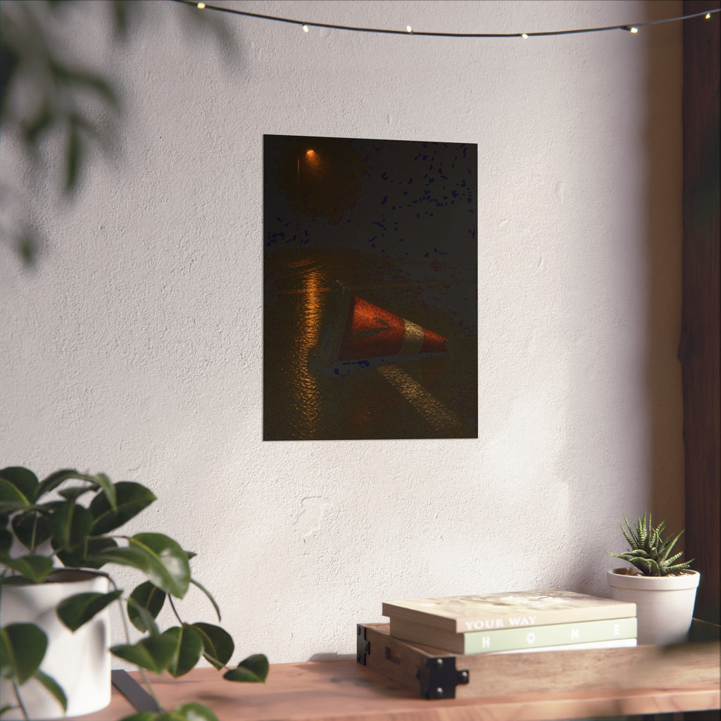A toppled orange traffic cone on a wet road under a lone streetlight. The Taking by the Bumper by Garabaggio, fine art print hanging in a room.