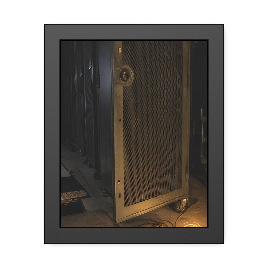 A perforated server rack door in a dark aisle lit by a floor work lamp. The Cold Aisle by Garabaggio, framed fine art print, 11″ x 14″.