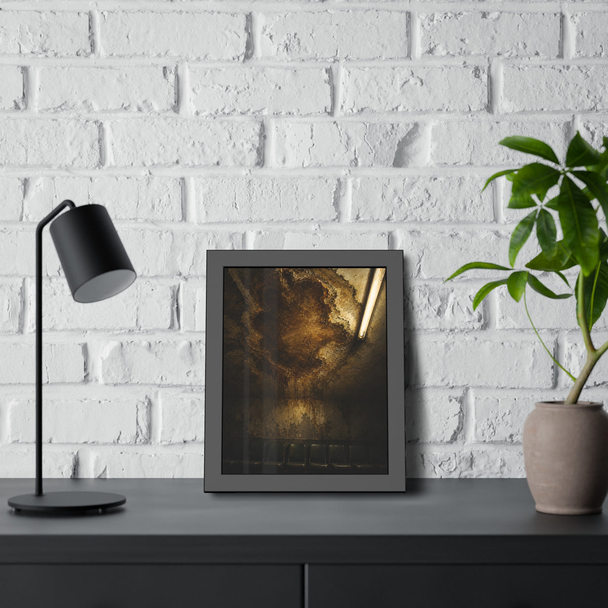 A brown water stain spreading across a ceiling above a row of chairs. The Stain Above the Row by Garabaggio, framed fine art print hanging in a room.