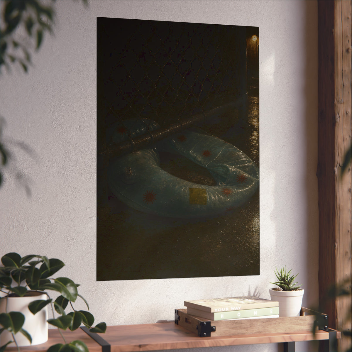 A deflated ring float pushed under a chain link fence in a wet alley. The Escape Beneath the Fence by Garabaggio, fine art print hanging in a room.