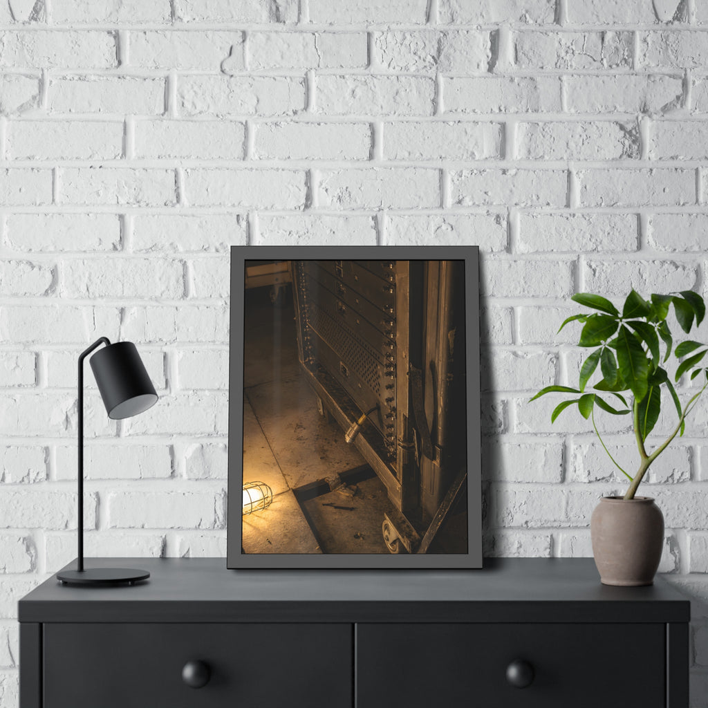 A server rack on a concrete floor beside a caged work light. The Silence at Cutover by Garabaggio, framed fine art print hanging in a room.