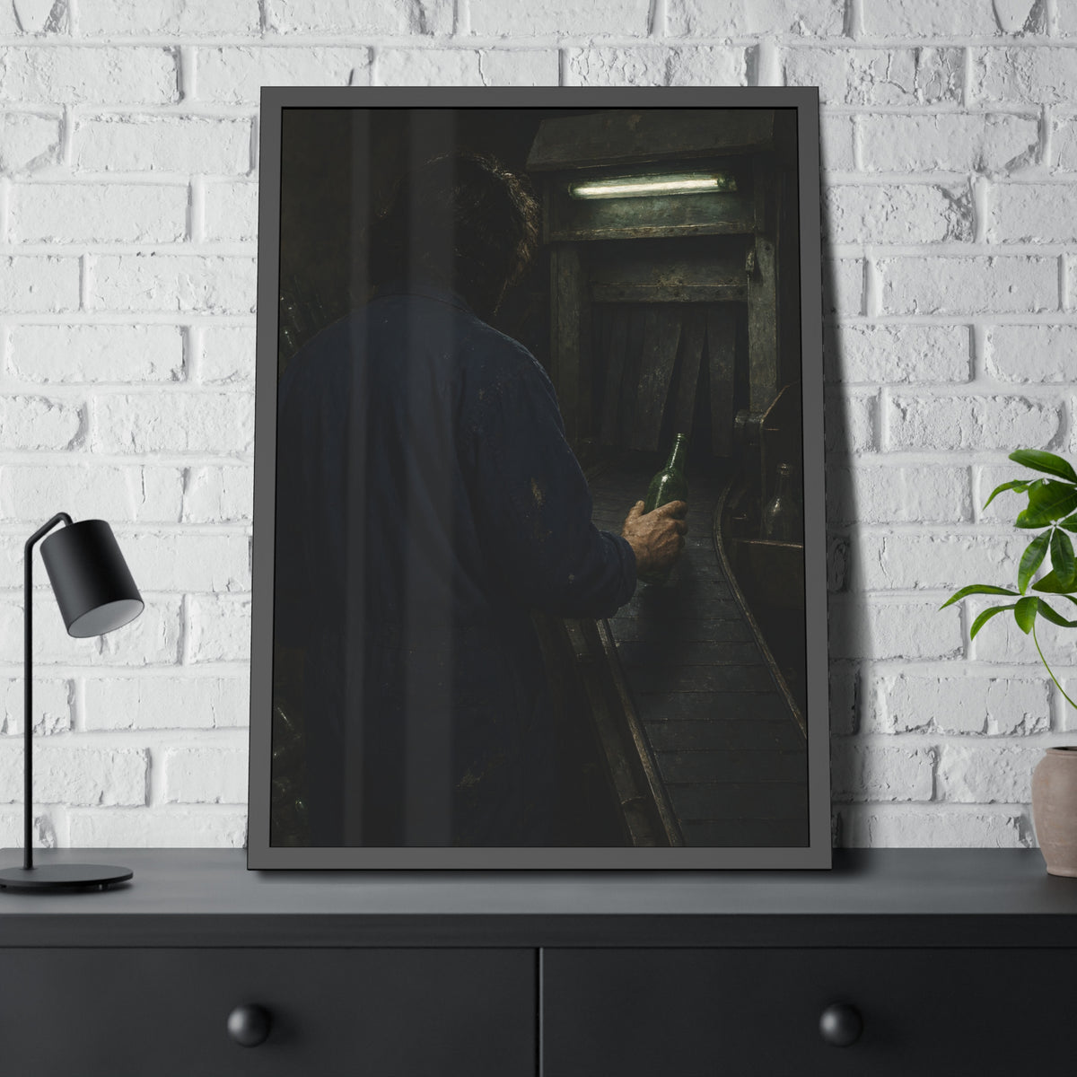 A man in coveralls sets a green bottle on a conveyor under a strip light. Garabaggio at the Conveyor by Garabaggio, framed fine art print hanging in a room.