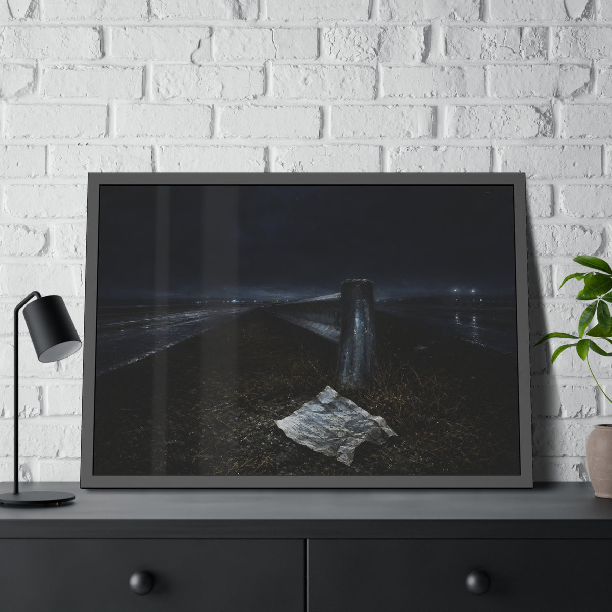 A sheet of paper on a grassy highway median beside a concrete post at night. The Resume on the Median by Garabaggio, framed fine art print hanging in a room.