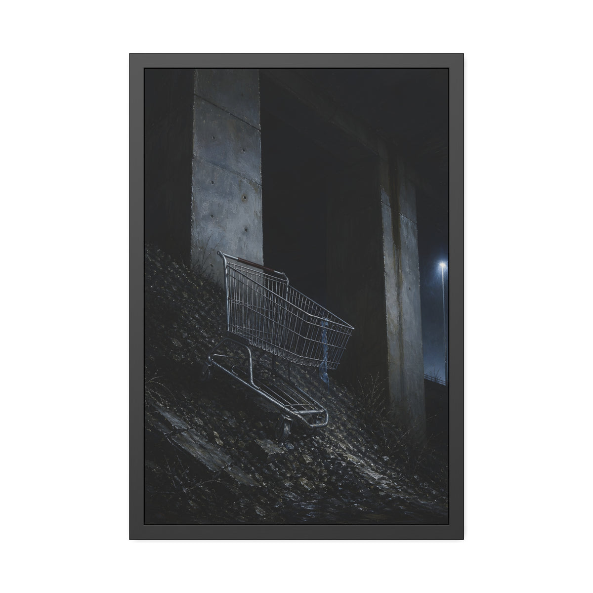 A shopping cart on a rocky slope under an overpass near a streetlamp. The Descent to the Underpass by Garabaggio, framed fine art print, 24″ x 36″.