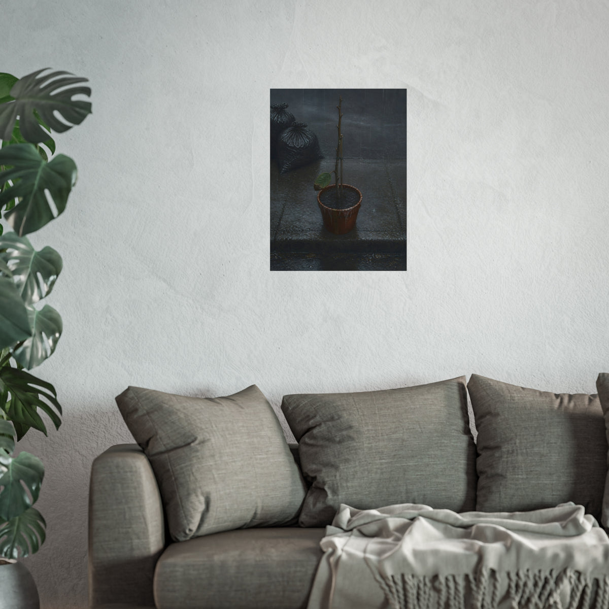 A near bare potted plant left out in the rain beside black garbage bags. The First Rain (Houseplant) by Garabaggio, fine art print hanging in a room.