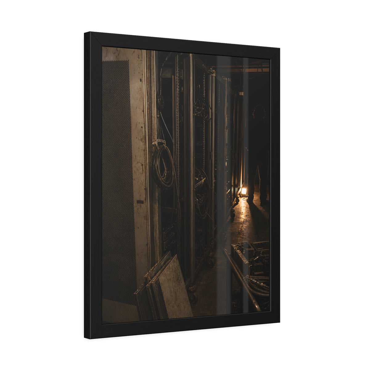 Open server racks in a dark room, a work lamp and a figure at the end. Garabaggio at the End of the Row by Garabaggio, framed fine art print hanging in a room.