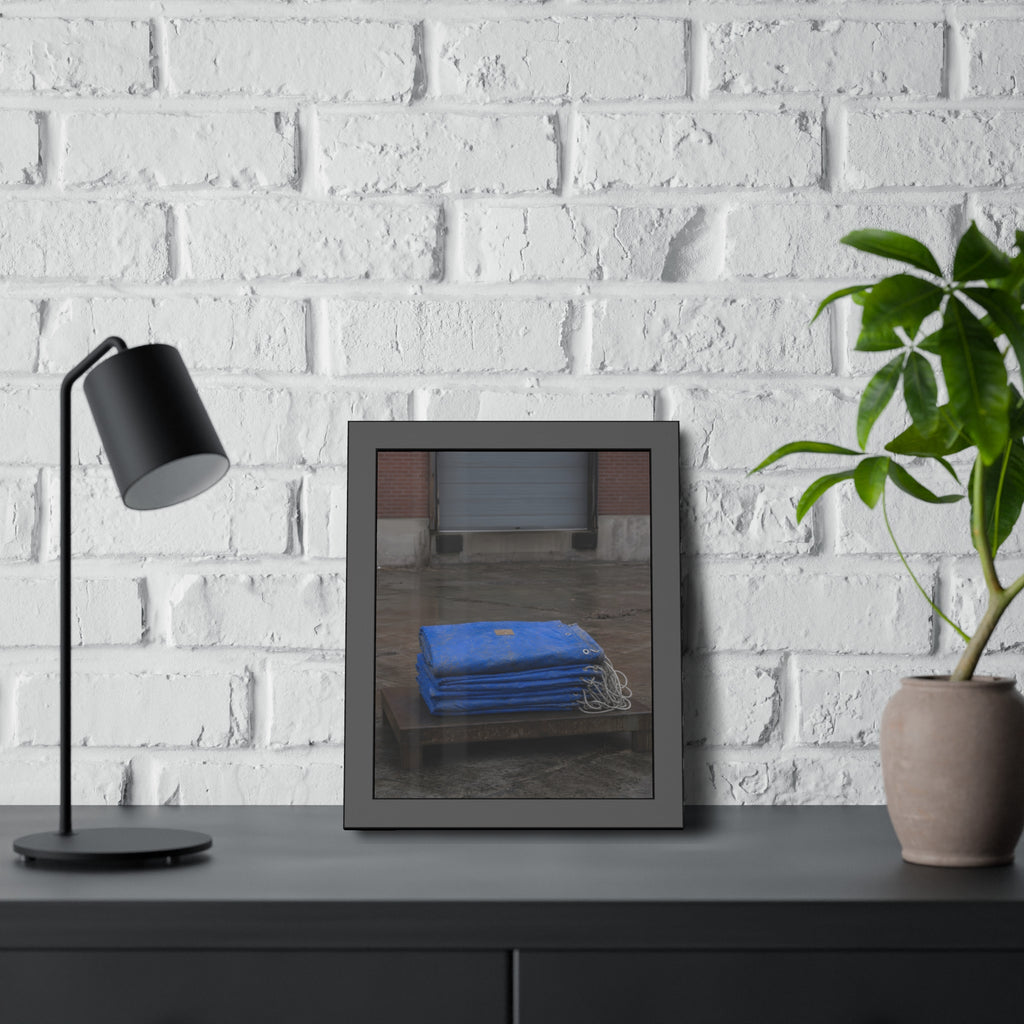 A folded blue tarp stacked on a low wooden platform by a loading dock. The Repaired Fold by Garabaggio, framed fine art print hanging in a room.
