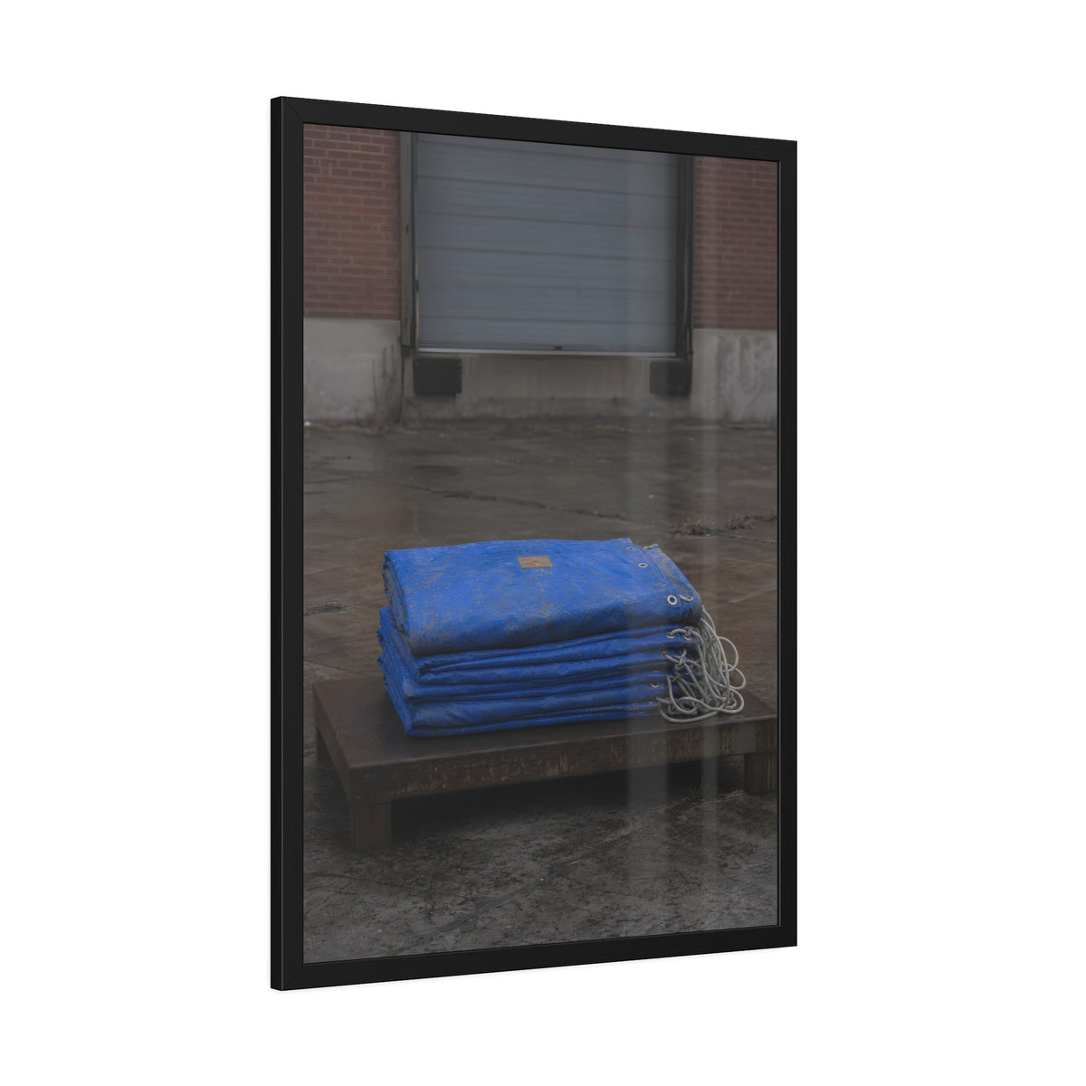 A folded blue tarp stacked on a low wooden platform by a loading dock. The Repaired Fold by Garabaggio, framed fine art print hanging in a room.