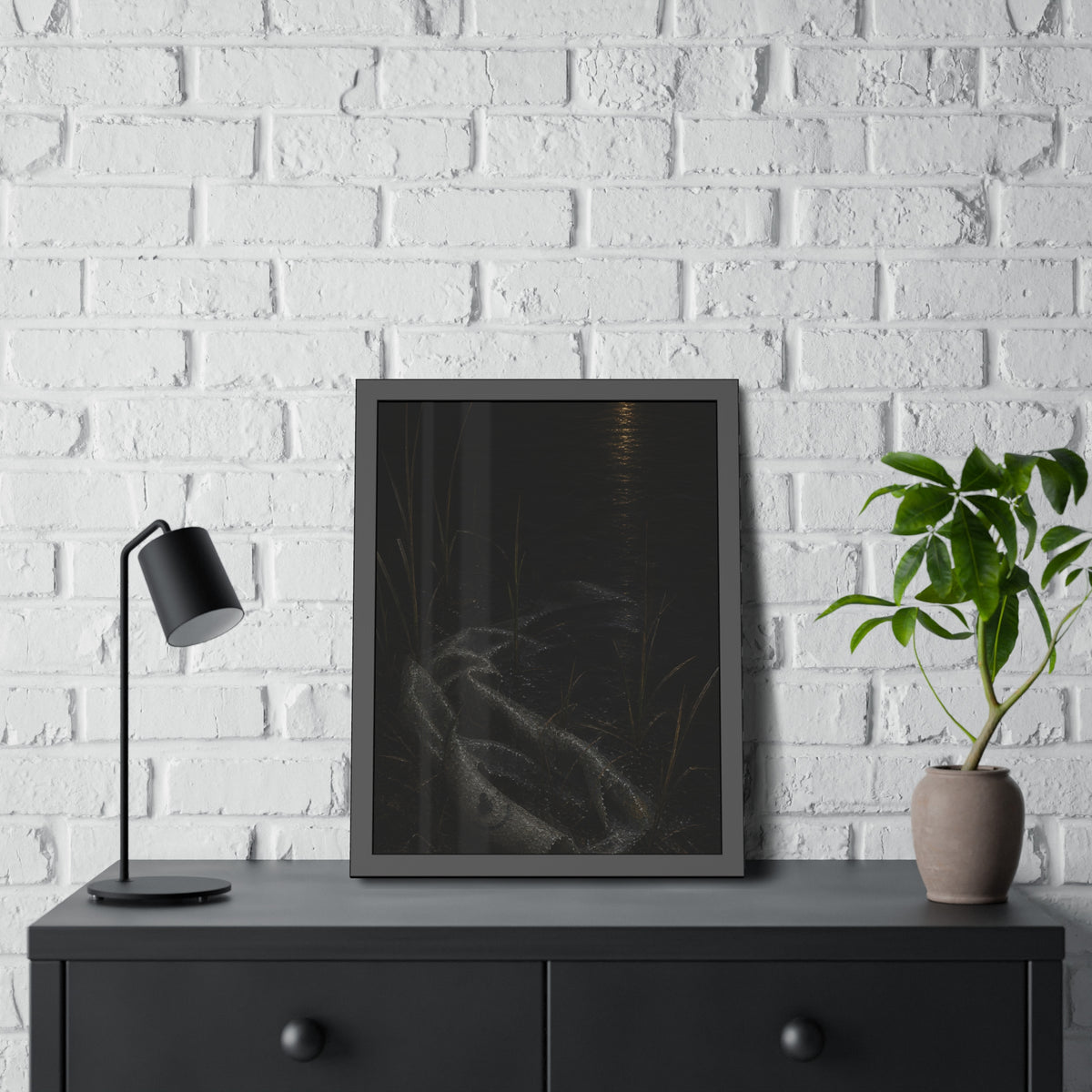 A deflated float slumped in lakeside reeds under a streak of moonlight. Spring Skin in the Reeds by Garabaggio, framed fine art print hanging in a room.