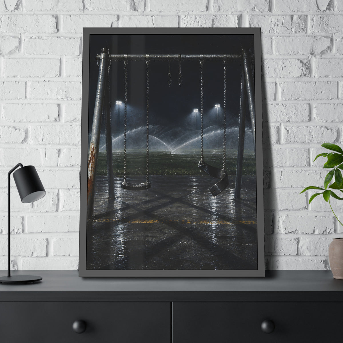 An empty swing set on wet asphalt, sprinklers arcing over the field. The Eleventh Hour: The Sprinklers by Garabaggio, framed fine art print hanging in a room.
