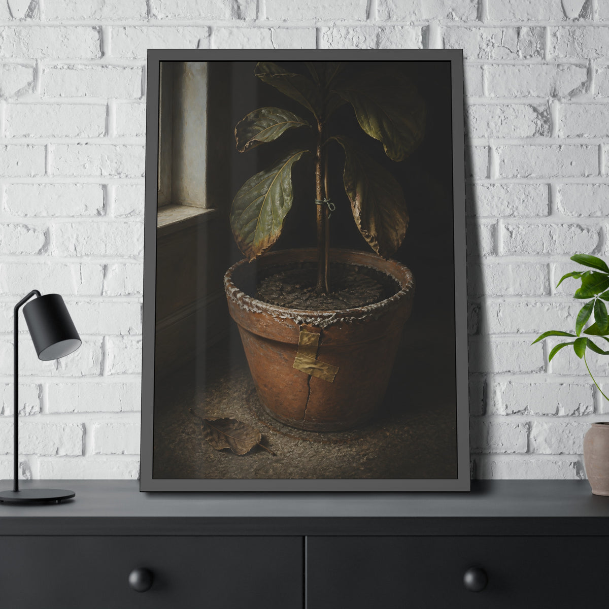 A drooping potted plant in a cracked terracotta pot beside a window. The Missed Watering by Garabaggio, framed fine art print hanging in a room.