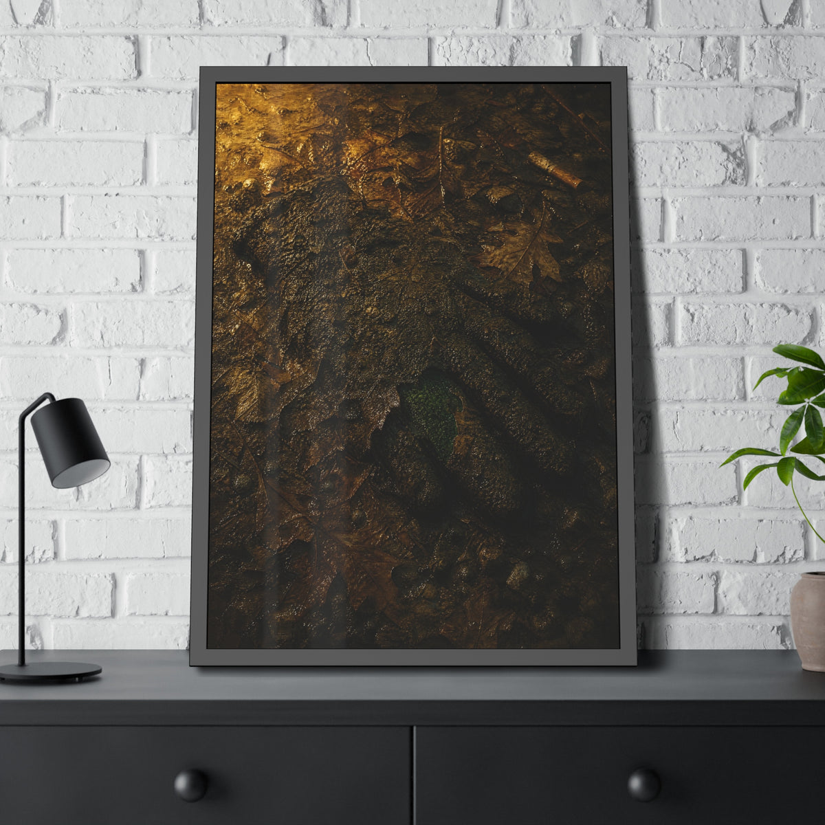 Wet mud and pressed oak leaves with a green scrap barely showing. The Reliquary of Mud and Leaf by Garabaggio, framed fine art print hanging in a room.
