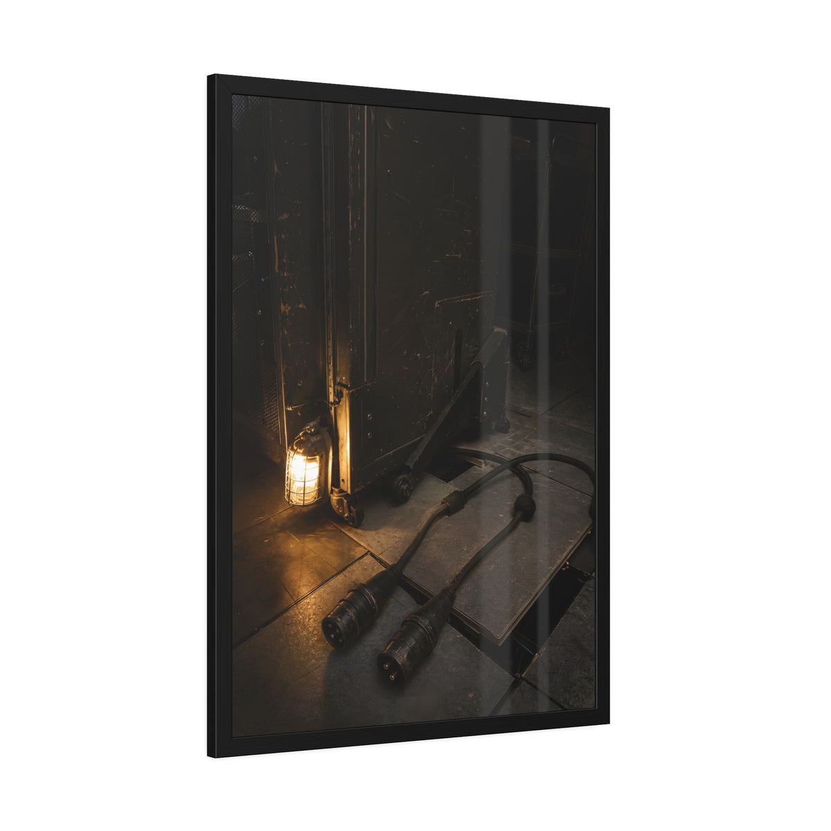 Two thick power cables unplugged on the floor beside a caged work lamp. The Redundant Power by Garabaggio, framed fine art print hanging in a room.