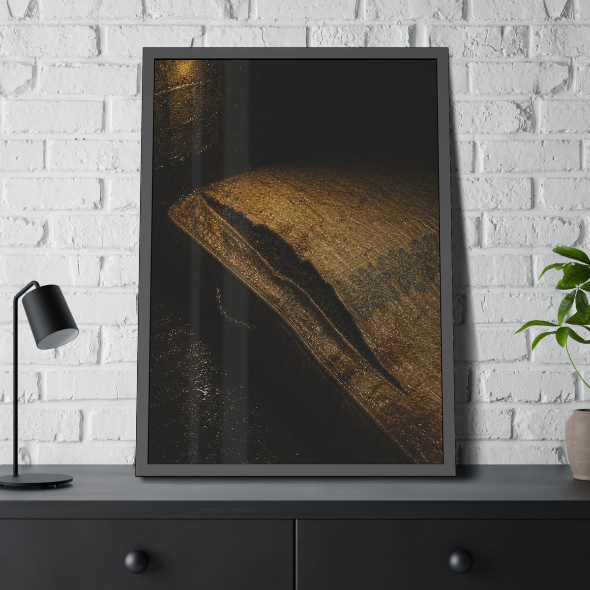 A mattress with its seam split open, lit warm against a dark wall. The Opening of the Ticking by Garabaggio, framed fine art print hanging in a room.