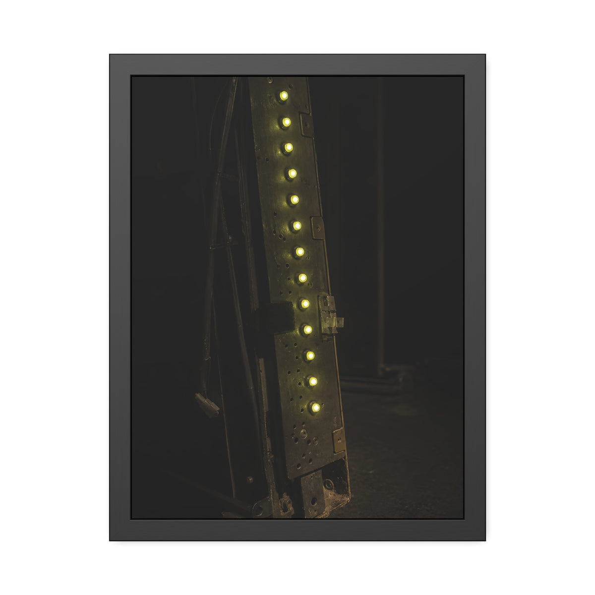 A dark rack panel with a vertical row of glowing green indicator lights. The First Green Choir by Garabaggio, framed fine art print, 18″ x 24″.