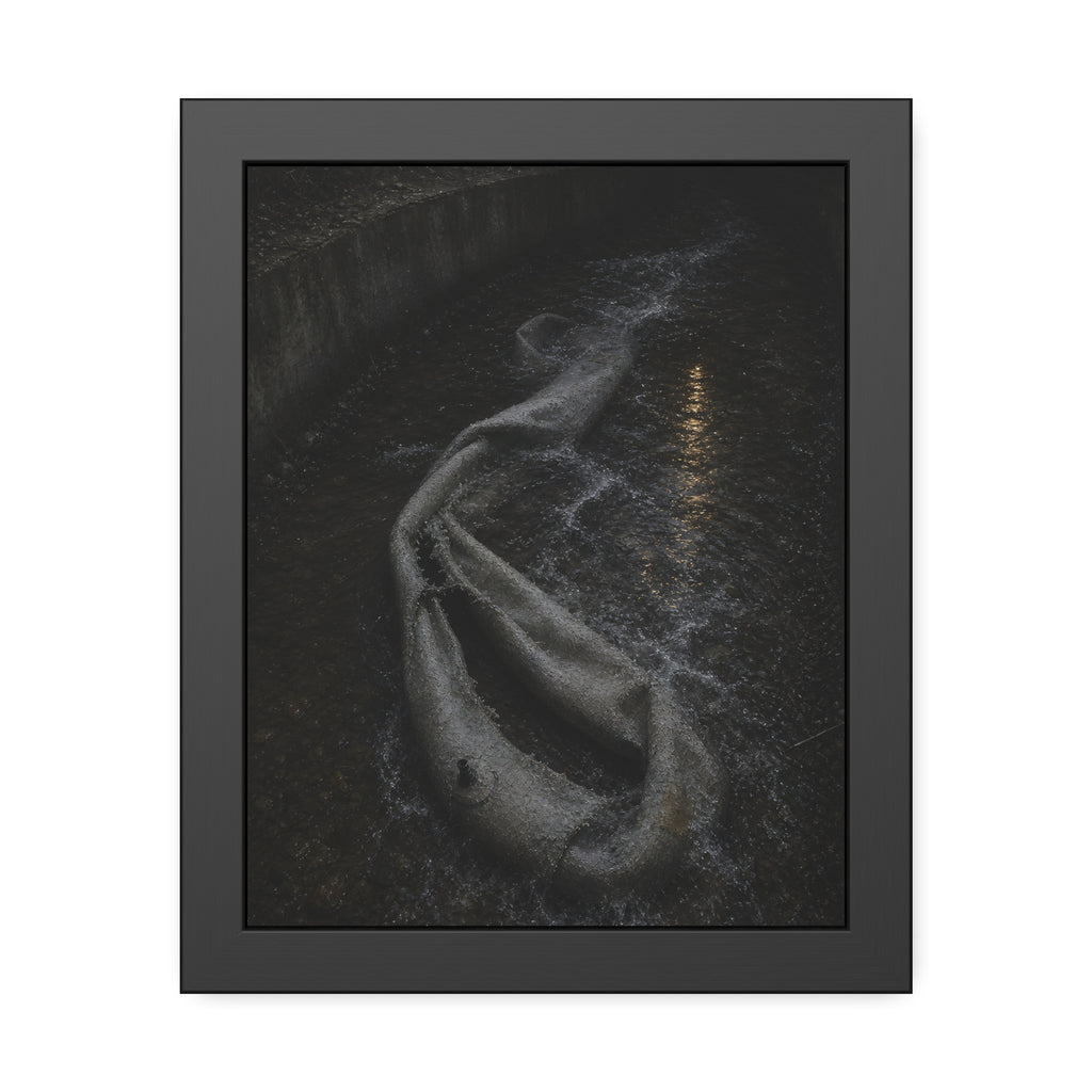 A deflated pool float caught in a concrete drainage channel of running water. The Release into Runoff by Garabaggio, framed fine art print, 11″ x 14″.