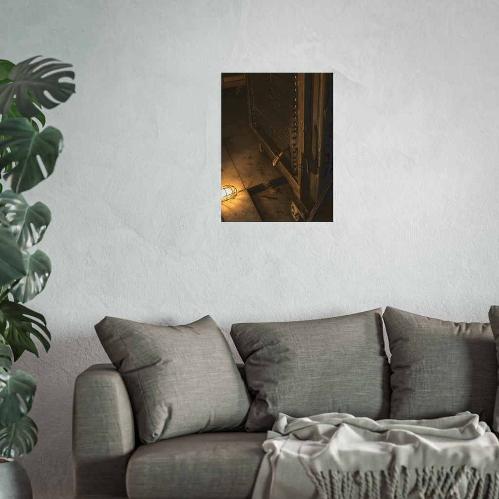 A server rack on a concrete floor beside a caged work light. The Silence at Cutover by Garabaggio, fine art print hanging in a room.