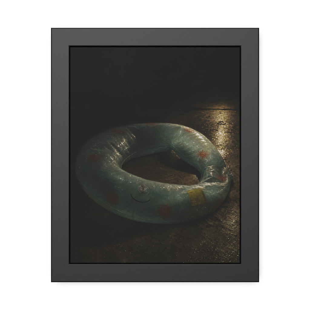 Deflated pool float ring on wet ground, lit from one side in the dark. After the Last Swim by Garabaggio, framed fine art print, 11″ x 14″.