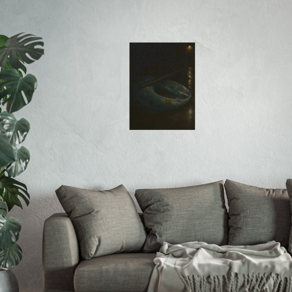 A deflated ring float pushed under a chain link fence in a wet alley. The Escape Beneath the Fence by Garabaggio, fine art print hanging in a room.