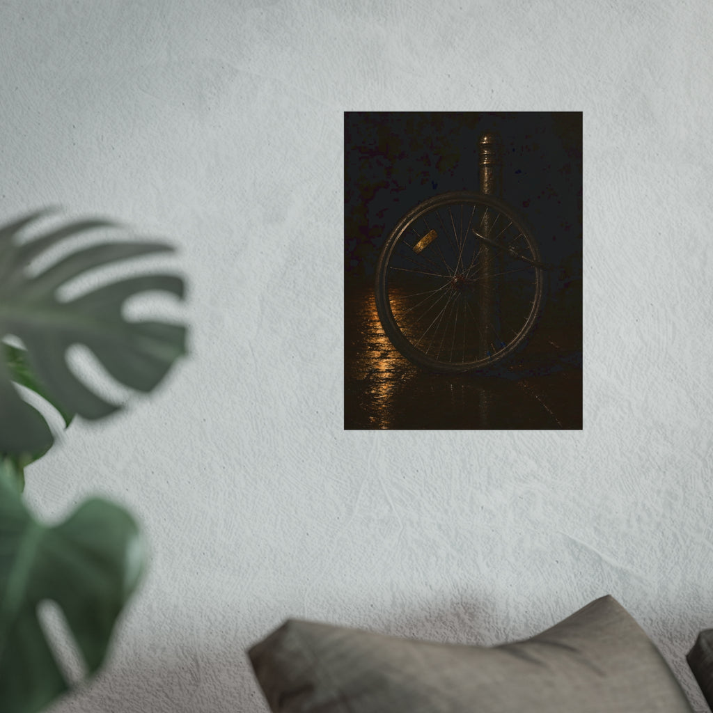 A bare bicycle wheel locked to a post on wet pavement. The Wheel Without a Bicycle by Garabaggio, fine art print hanging in a room.
