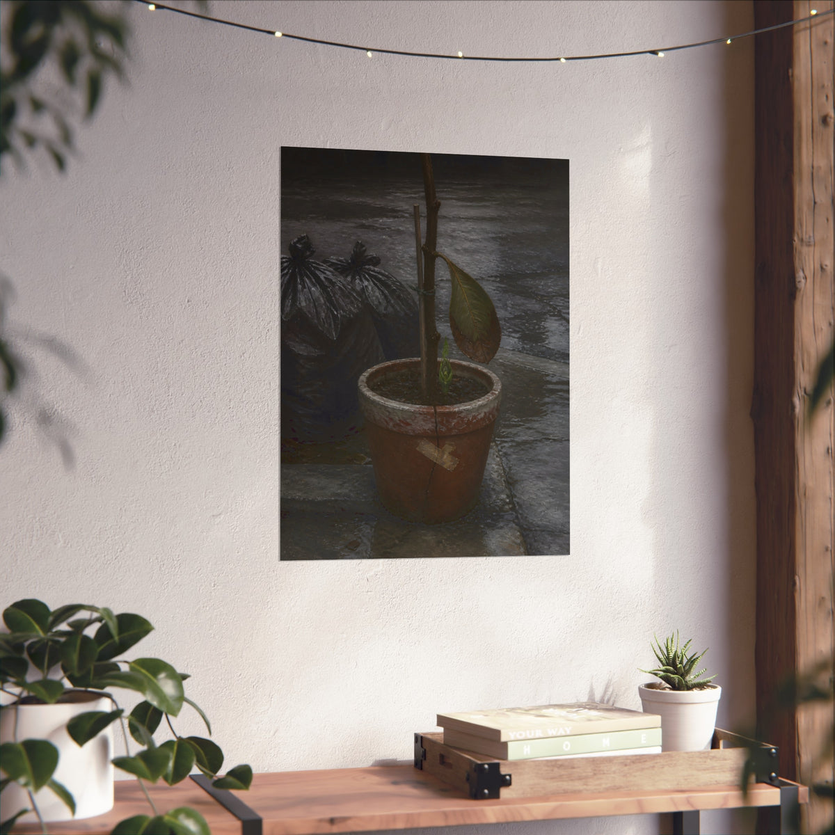 A taped clay pot with one leaf and a green shoot on wet pavement. The Green at the Base by Garabaggio, fine art print hanging in a room.