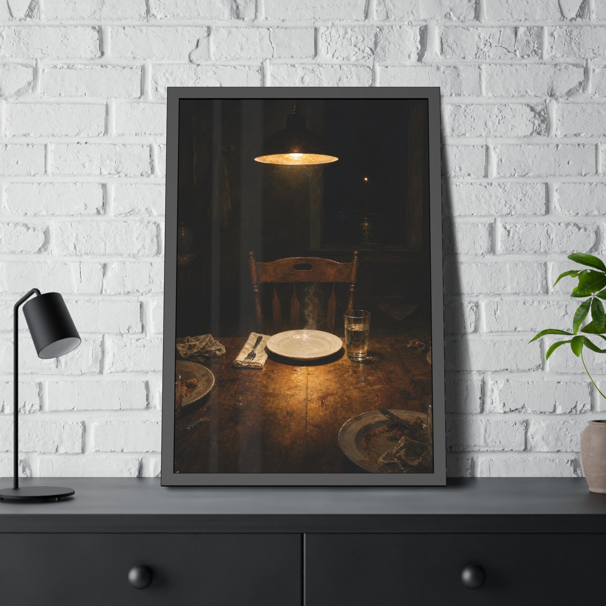 A clean plate and empty chair under a hanging lamp at a used dinner table. The Empty Seat at Dinner by Garabaggio, framed fine art print hanging in a room.