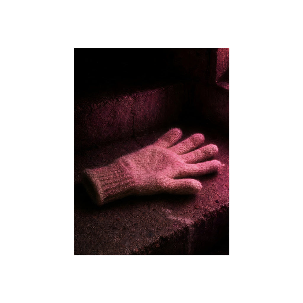 A knitted glove lying flat on a concrete step under pink light. The Vigil in Pink Light by Garabaggio, fine art print hanging in a room.