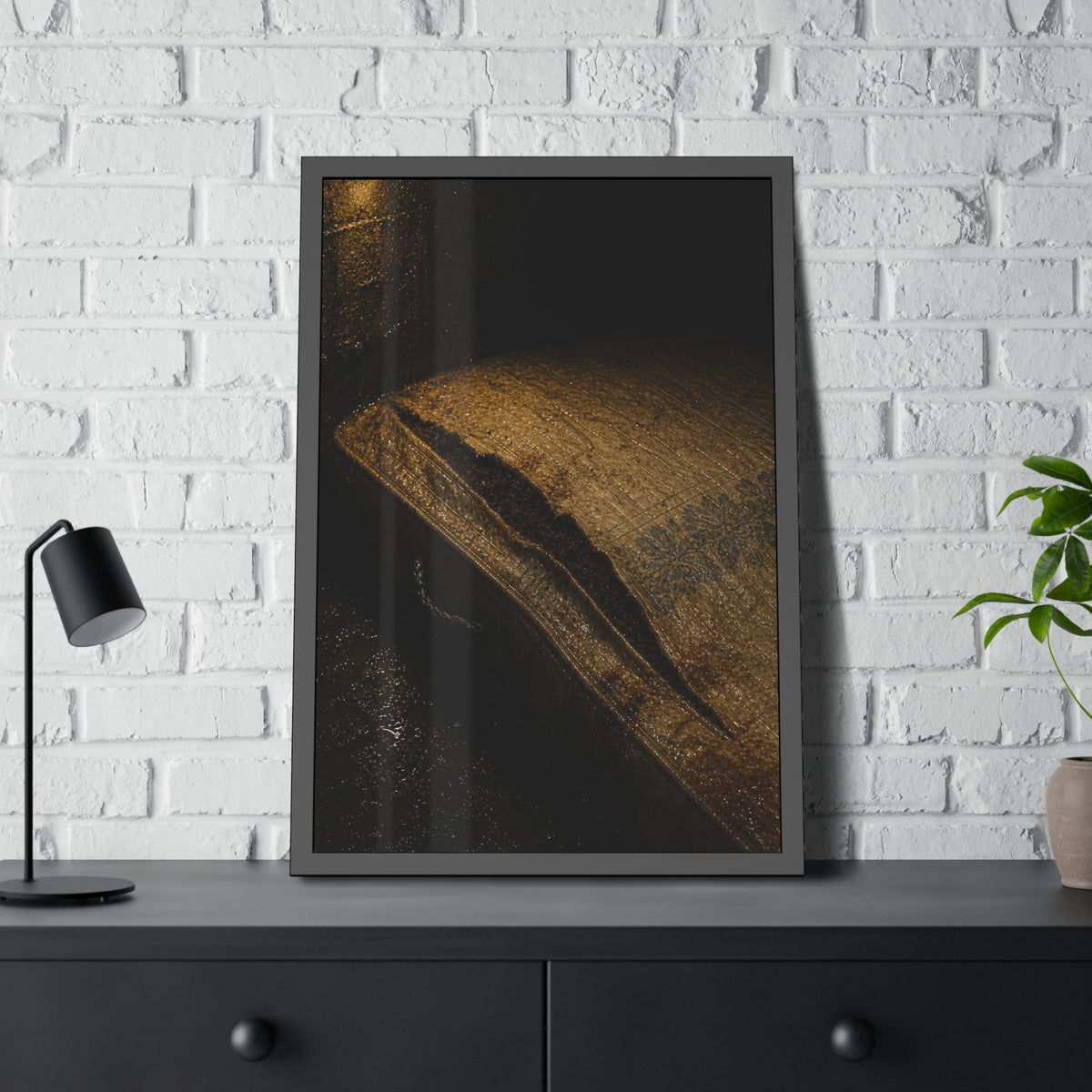 A mattress with its seam split open, lit warm against a dark wall. The Opening of the Ticking by Garabaggio, framed fine art print hanging in a room.