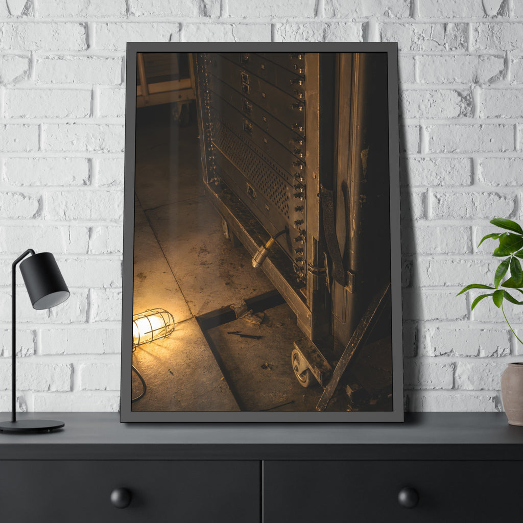 A server rack on a concrete floor beside a caged work light. The Silence at Cutover by Garabaggio, framed fine art print hanging in a room.