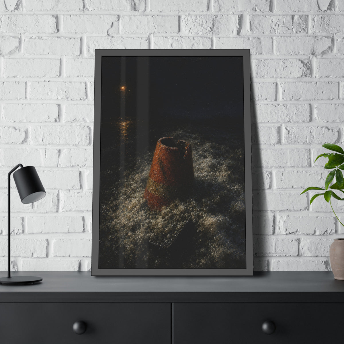 An orange traffic cone half buried in road salt under a distant streetlight. The Burial in Road Salt by Garabaggio, framed fine art print hanging in a room.
