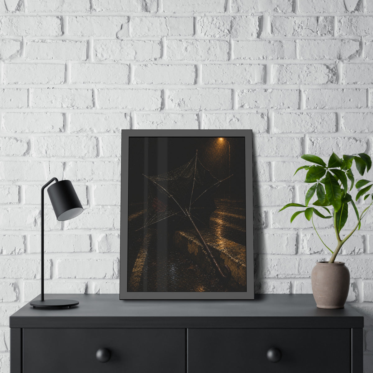 A broken umbrella inside out on a wet curb under a street lamp. The Inversion at the Median by Garabaggio, framed fine art print hanging in a room.