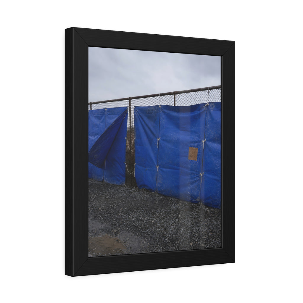 Blue tarps lashed to a chain link fence above gravel under grey sky. Drapery on the Fence by Garabaggio, framed fine art print hanging in a room.