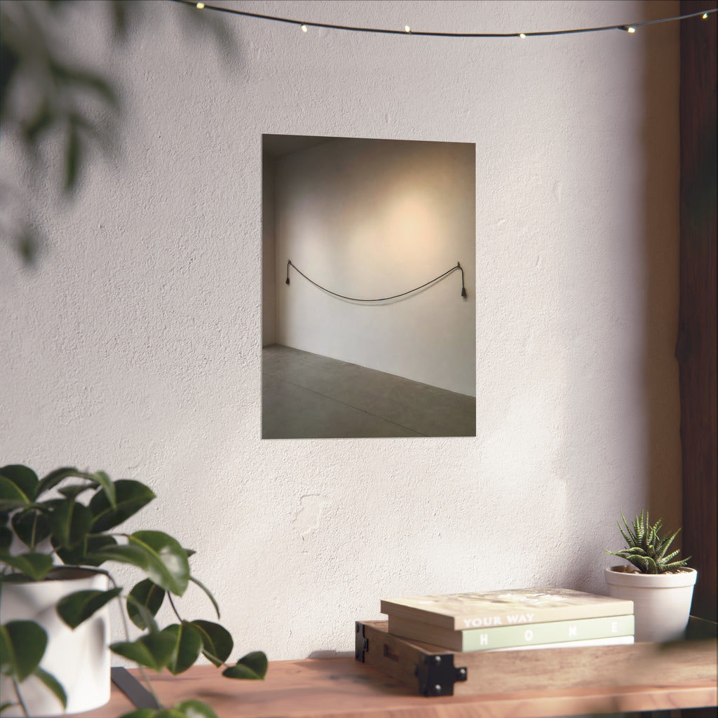 An extension cord hung in a long slack curve across a bare white wall. The Unplugged Line by Garabaggio, fine art print hanging in a room.