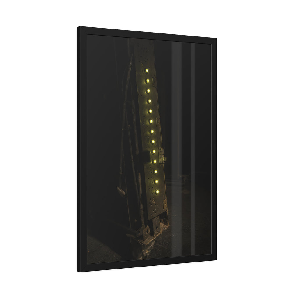 A dark rack panel with a vertical row of glowing green indicator lights. The First Green Choir by Garabaggio, framed fine art print hanging in a room.