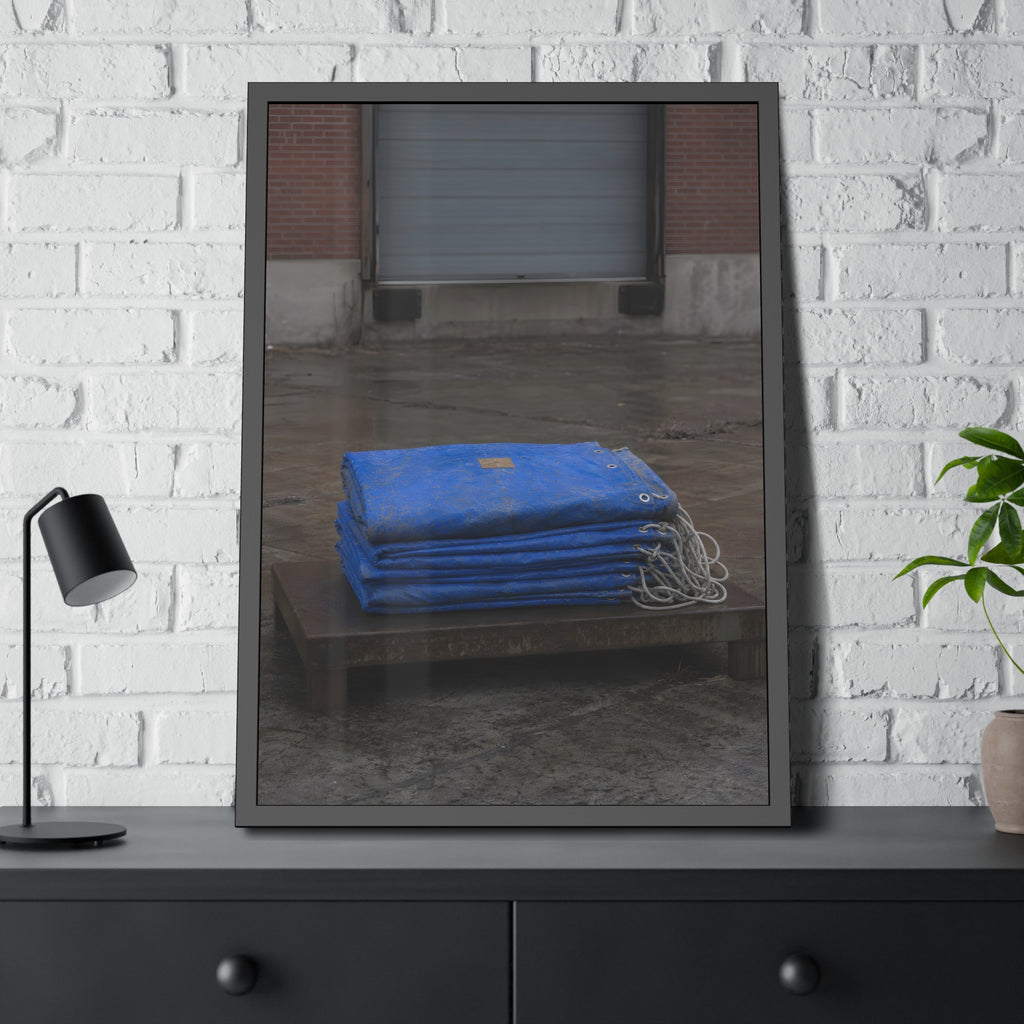 A folded blue tarp stacked on a low wooden platform by a loading dock. The Repaired Fold by Garabaggio, framed fine art print hanging in a room.