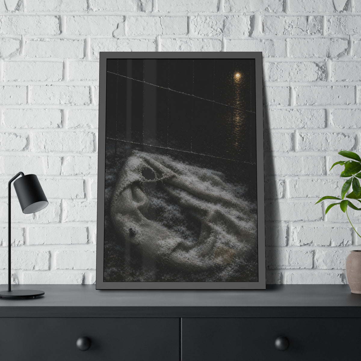 A deflated pool float under snow beside a chain link fence at night. The Bleaching Under Snow by Garabaggio, framed fine art print hanging in a room.
