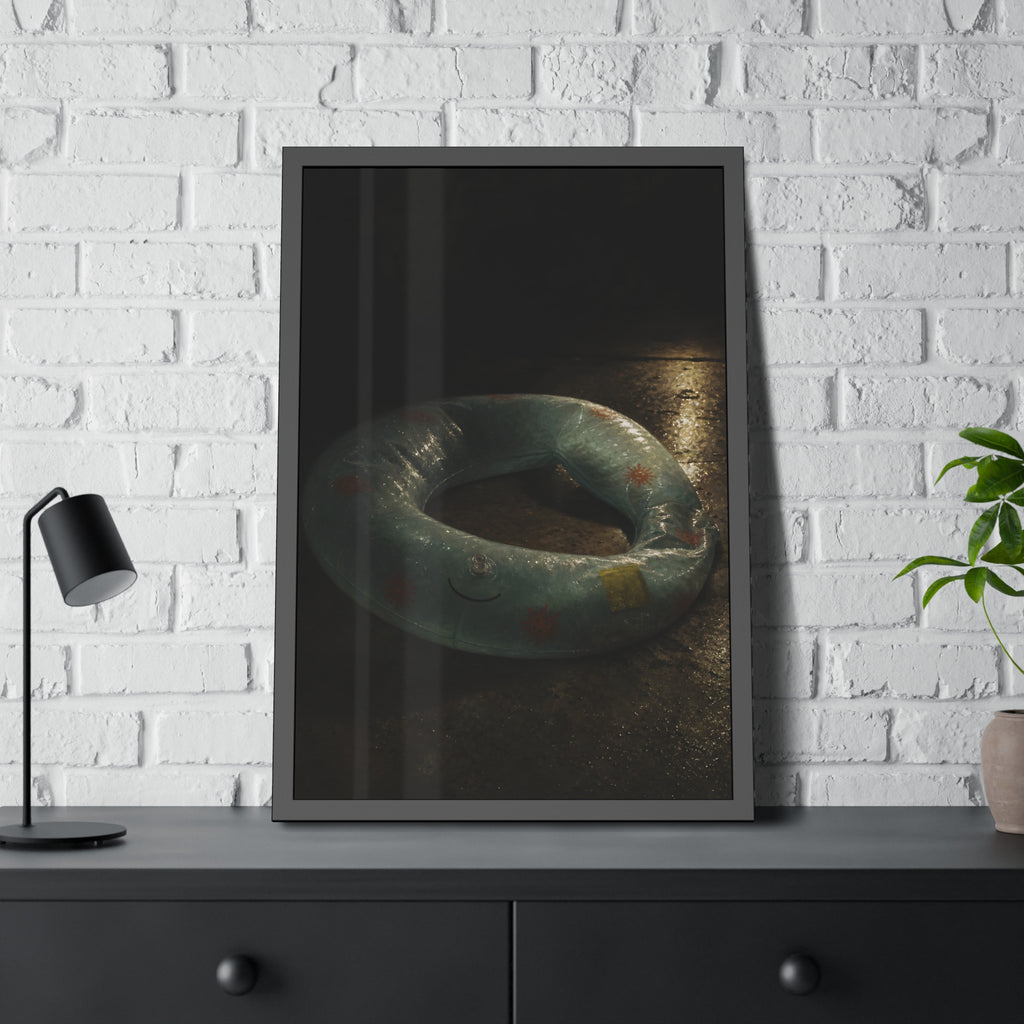 Deflated pool float ring on wet ground, lit from one side in the dark. After the Last Swim by Garabaggio, framed fine art print hanging in a room.