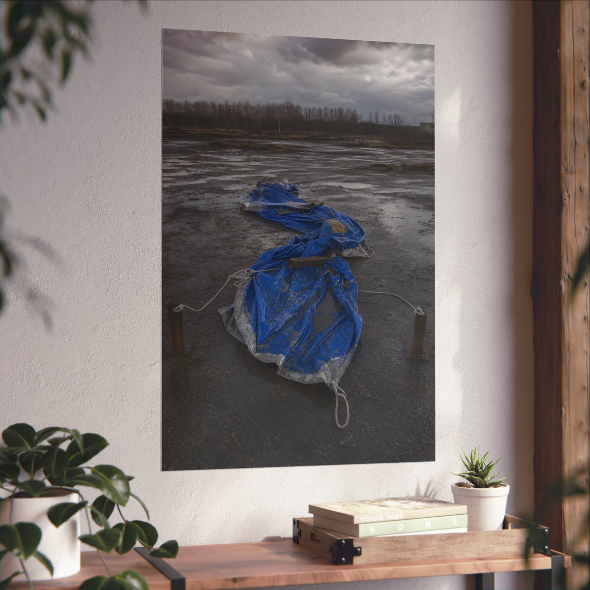 Collapsed blue tarp roped between two posts on wet cracked ground. Collapse Under Wind by Garabaggio, fine art print hanging in a room.