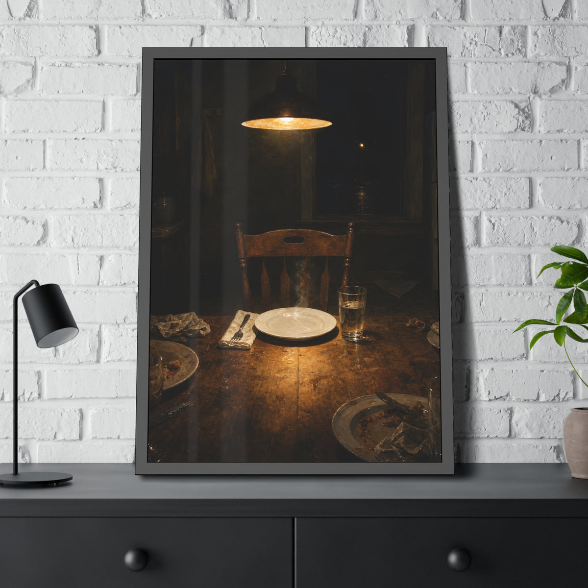 A clean plate and empty chair under a hanging lamp at a used dinner table. The Empty Seat at Dinner by Garabaggio, framed fine art print hanging in a room.