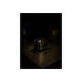 A scorched chrome toaster alone on a metal counter in a dark room. The Cooling on Steel by Garabaggio, fine art print, 12″ x 16″.